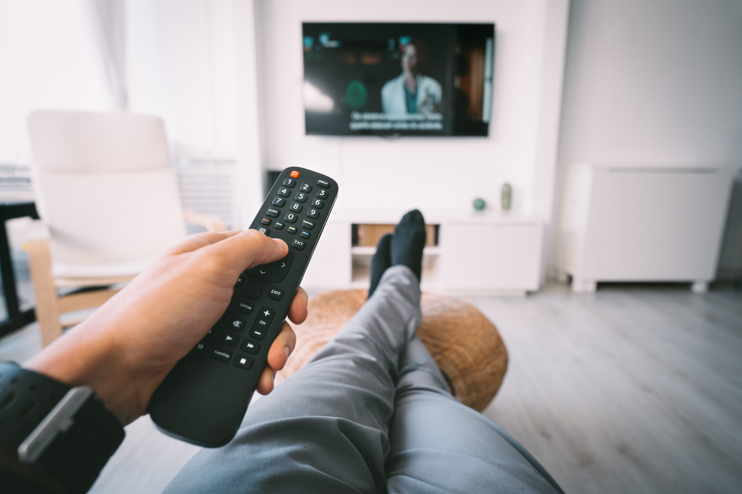 man sitting on sofa and watching tv with remote controller in his hand. rest at home.